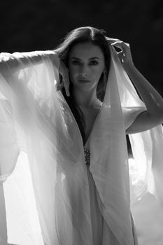 Black and white portrait of a woman in tulle, elegantly posing with sunlight highlighting her features.