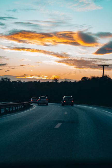Cars travel along a peaceful highway at sunset with breathtaking sky views.