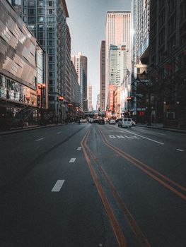 A view of an empty urban street flanked by tall skyscrapers in downtown Chicago.