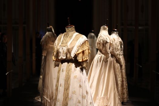 An array of vintage dresses elegantly displayed on mannequins in a dimly lit setting.