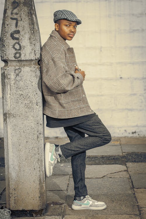 Model in a Checkered Coat Posing on the Sidewalk