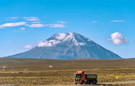 A red semi-truck drives near the towering Misti Volcano in Arequipa, Peru.