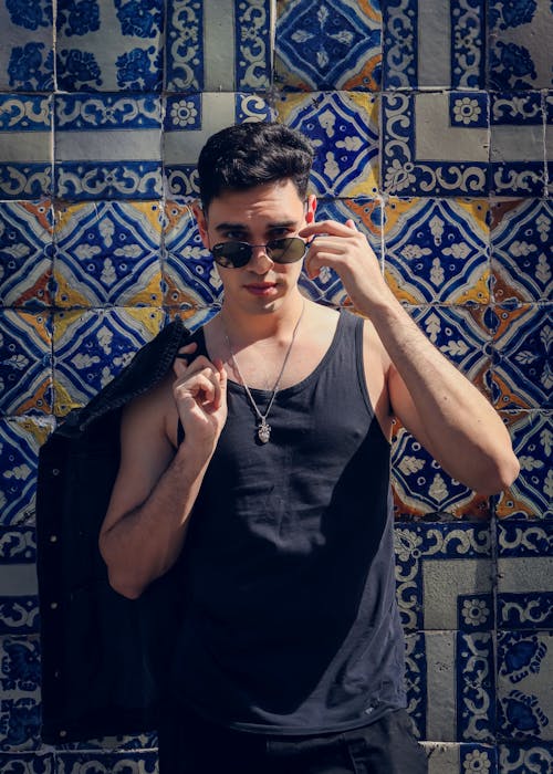 Young Man in a Black Tank Top in Front of a Wall Covered with Decorative Tiles