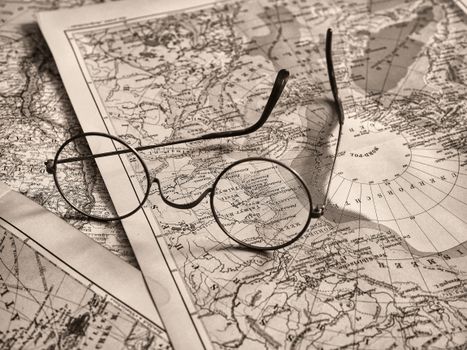 Round eyeglasses rest on an antique world map, evoking a sense of exploration.
