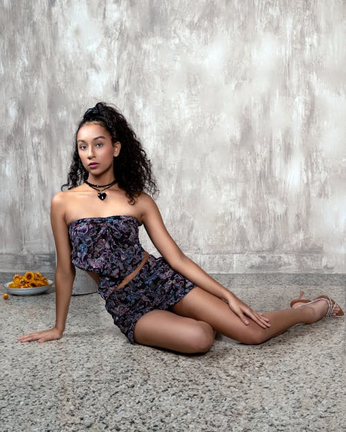 Young Model in a Patterned Mini Dress Sitting on the Floor