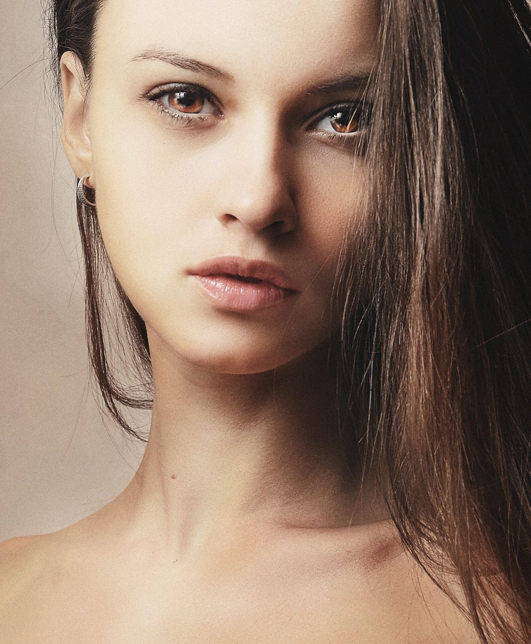 Close-up portrait of a young woman with brunette hair, showcasing natural beauty and elegance.