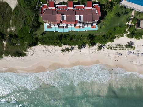 Top-down view of a beachfront mansion with pool and palm trees in Playa del Carmen, México.