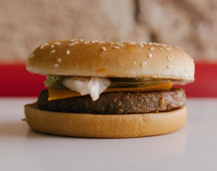 Close-up of a tasty cheeseburger with lettuce and tomato on a sesame seed bun.