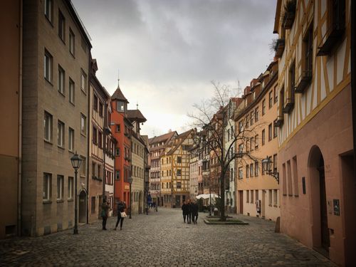 Free Historic cobblestone street in Nuremberg showcasing medieval architecture with people strolling. Stock Photo