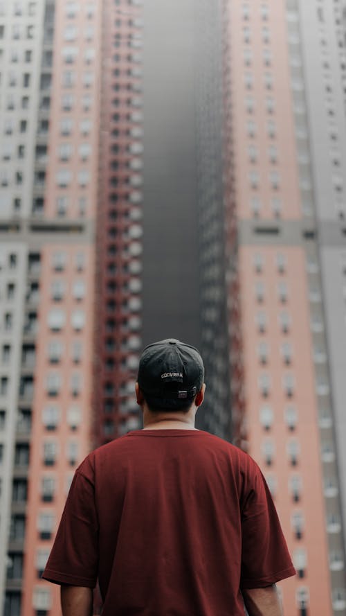 Skyscraper behind Man in Cap and T-shirt