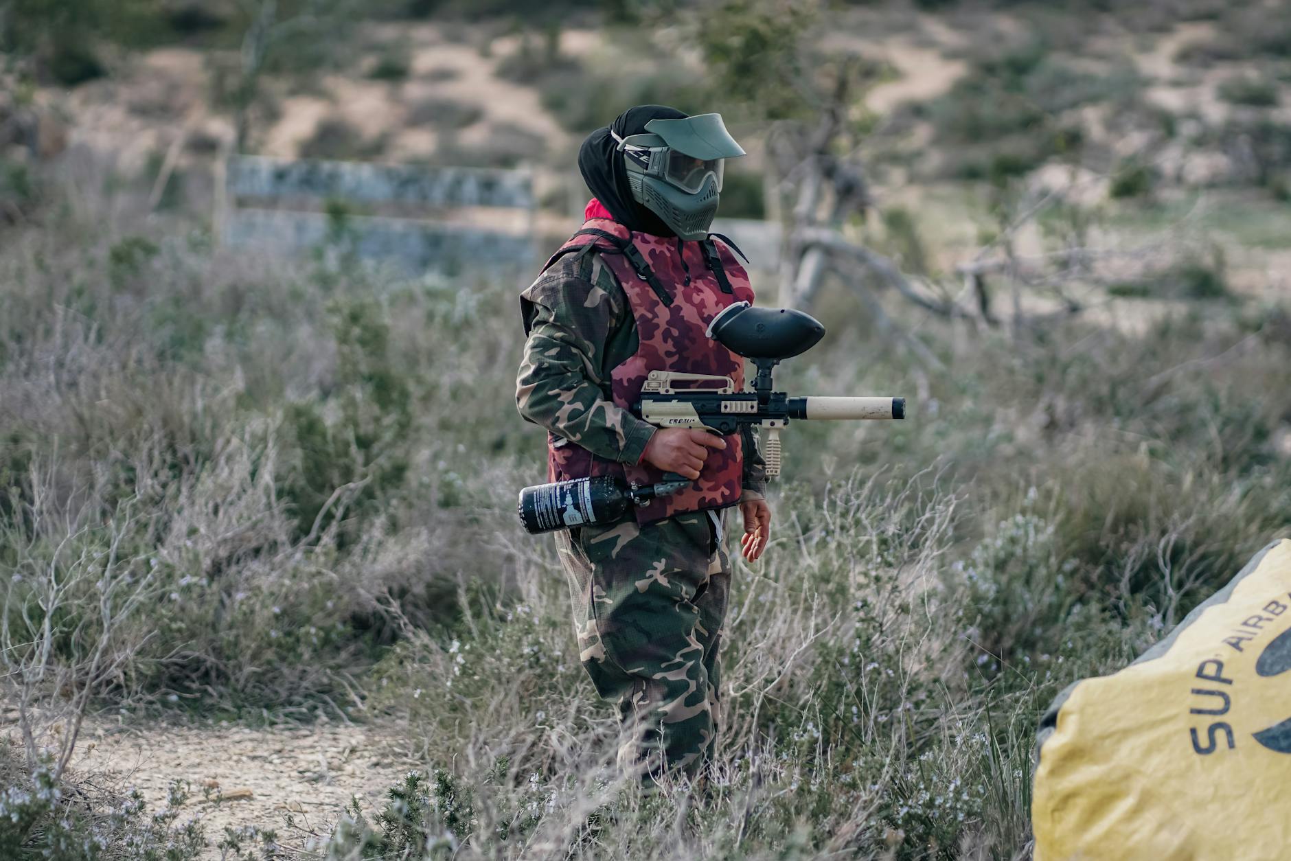A man in camouflage gear holding a paintball gun