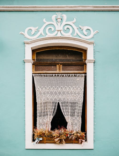 Window with lace curtains and flowers on the wall