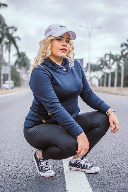 Woman Squatting on Asphalt Road