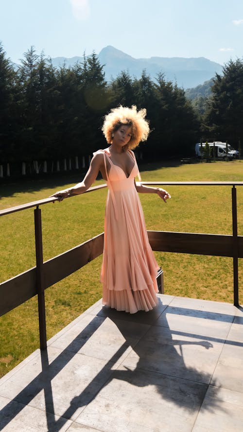 Elegant Woman in a Pink Dress Posing in a Park 