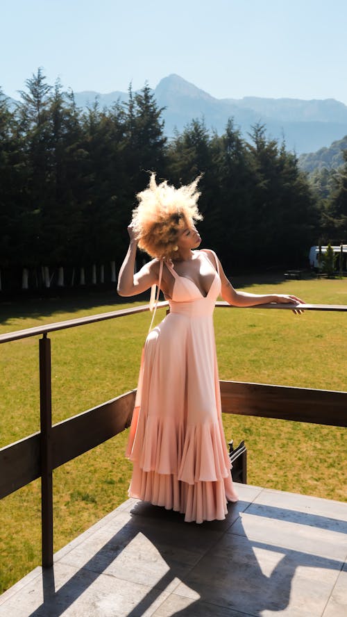 Young Woman in a Pink Dress Posing on a Terrace 