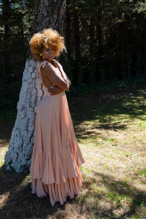 Elegant Woman in a Pink Dress Posing in a Park 