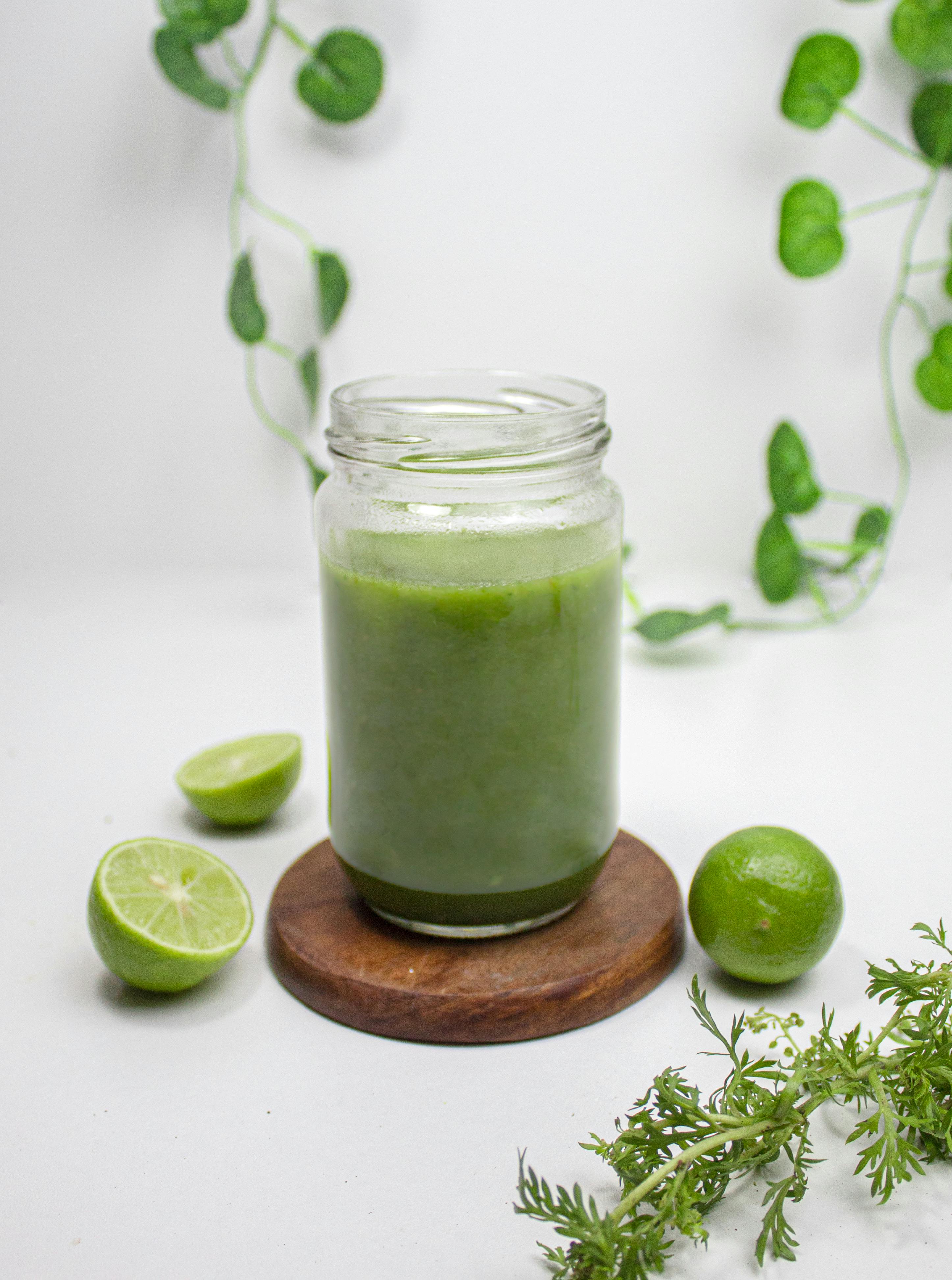 Green smoothie in a jar with limes and herbs for a healthy lifestyle on a white background.