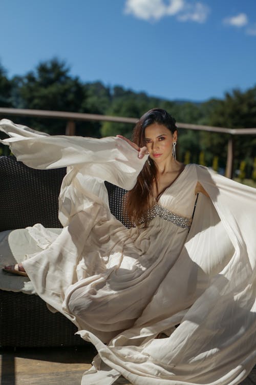 A woman in a long white dress is sitting on a chair