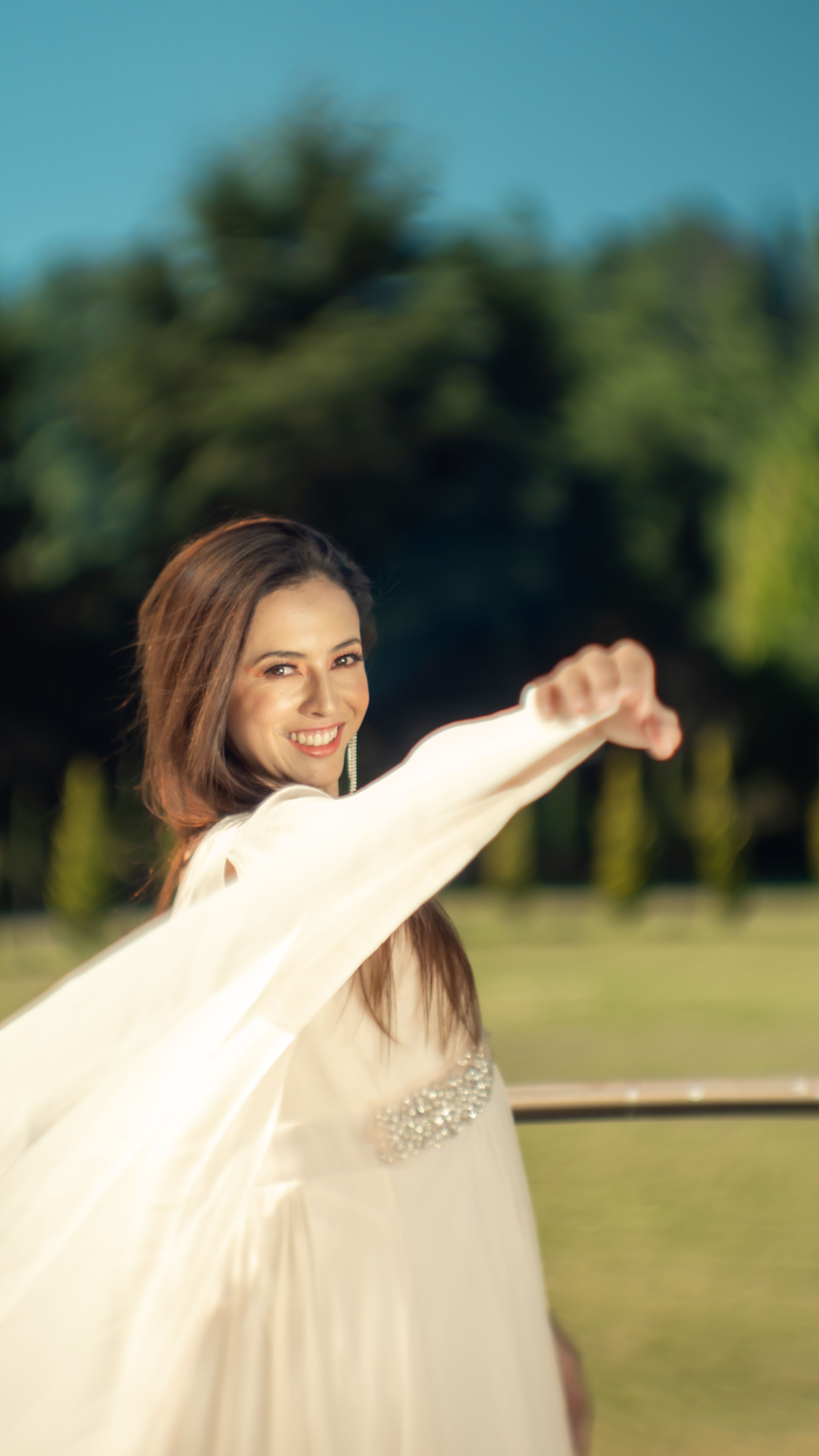 A fashion model in a flowing white dress smiling outdoors in Ciudad de México, CDMX.