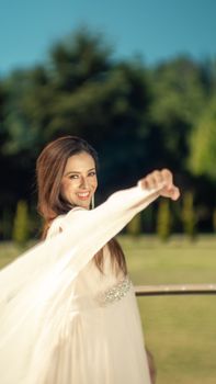A fashion model in a flowing white dress smiling outdoors in Ciudad de México, CDMX.