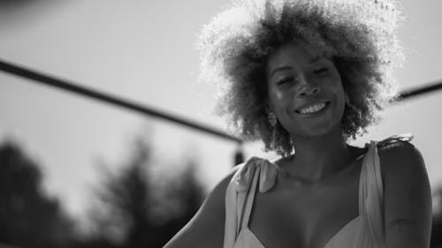A woman with curly hair smiling in a black and white photo