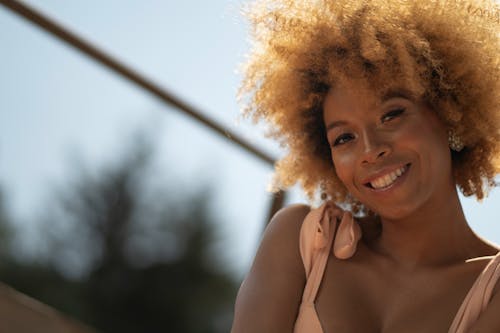 A woman with curly hair smiling and looking at the camera
