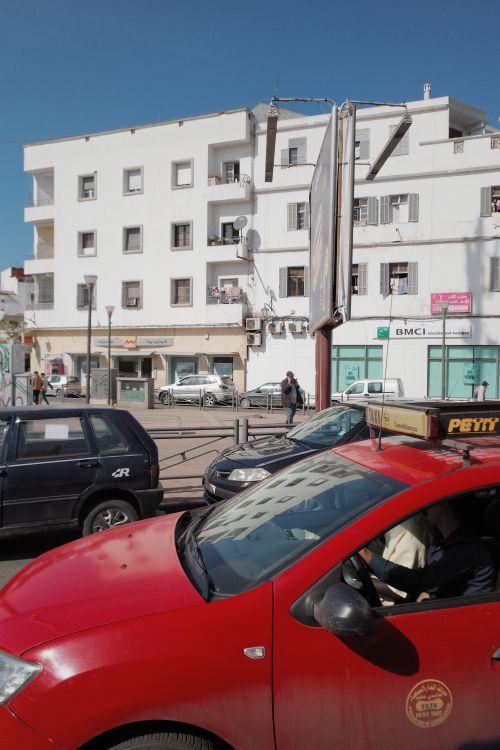 Free Lively city street with parked cars and a white building under a clear sky. Stock Photo