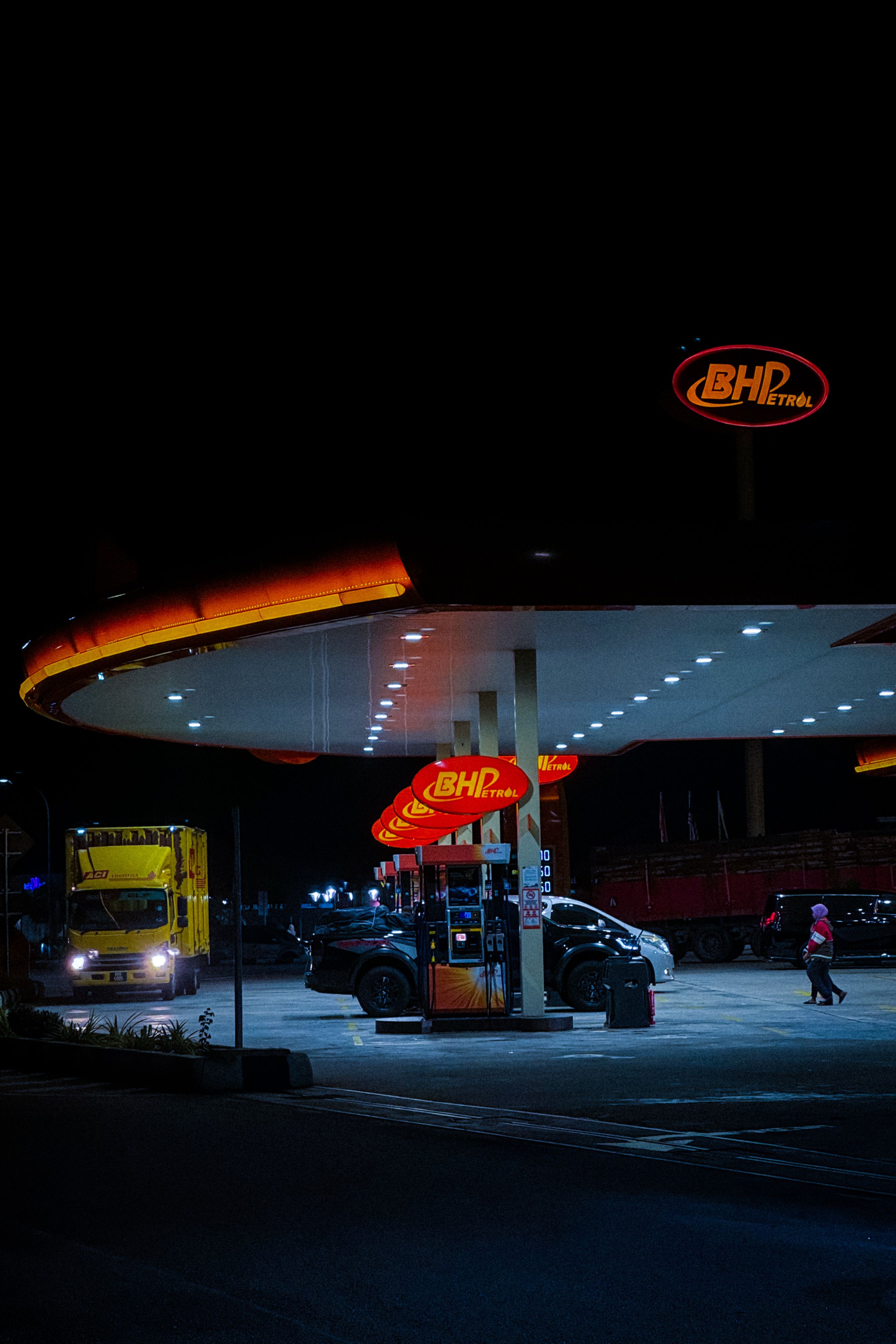 Posto de gasolina BHPetrol iluminado com veículos à noite em Sungkai, Malásia.