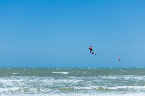 Free A kitesurfer jumps high above the ocean waves, showcasing adventure and skill in a vibrant coastal setting. Stock Photo