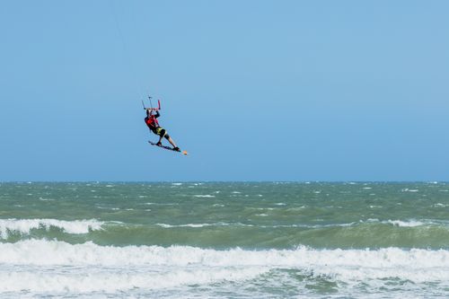 Free A kitesurfer performing a high jump over ocean waves under a clear sky. Stock Photo