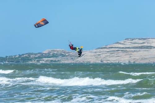 A person kite surfing in the ocean with a mountain in the background