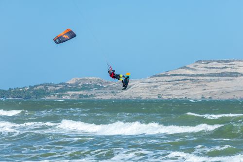 Free Thrilling kitesurfing action captured as a sportsman performs stunts over ocean waves. Stock Photo
