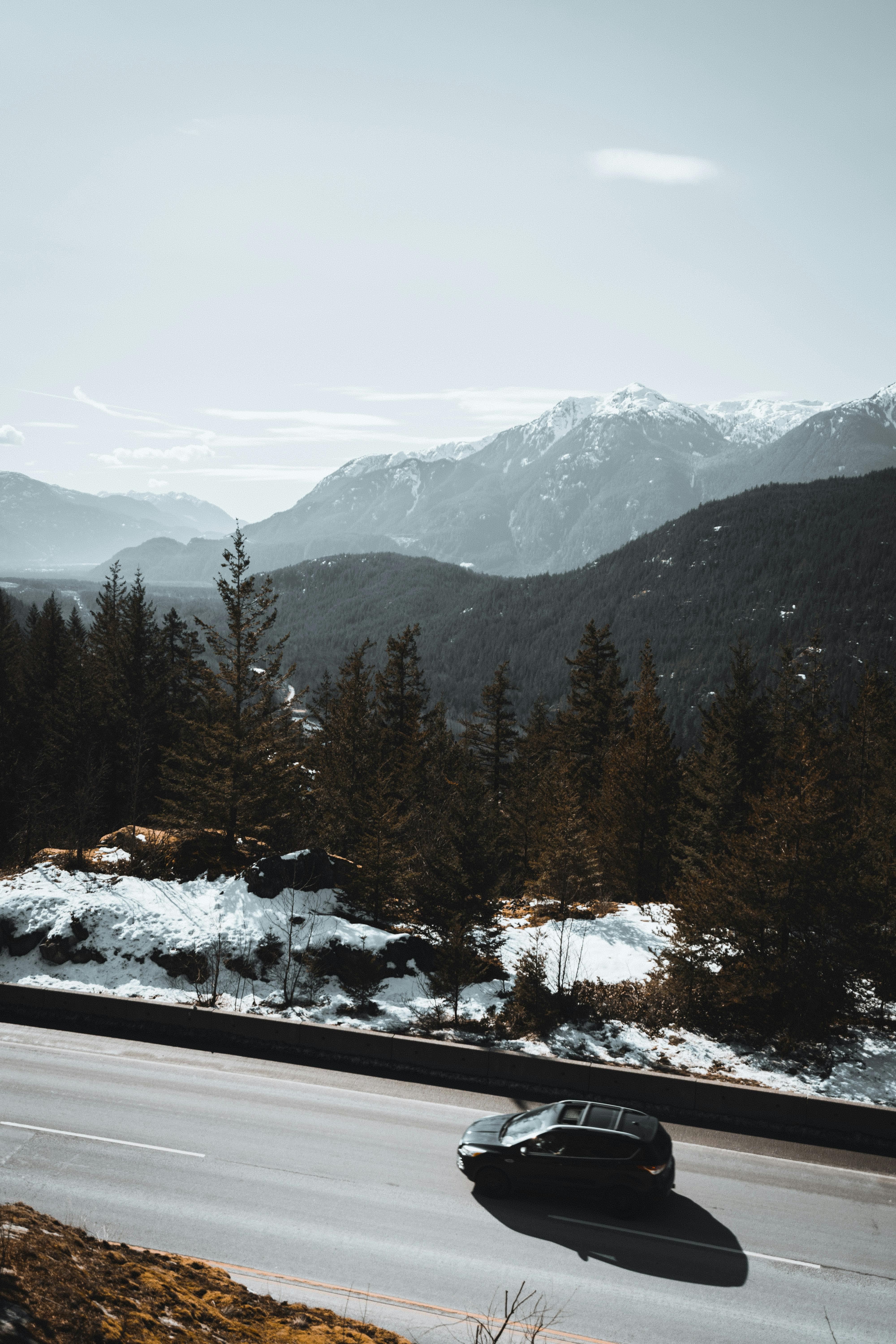 一辆汽车行驶在风景优美的山路上，远处白雪皑皑的山峰令人惊叹