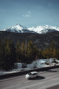 汽车行驶在雪山中，沿途的树木和山峰风景优美