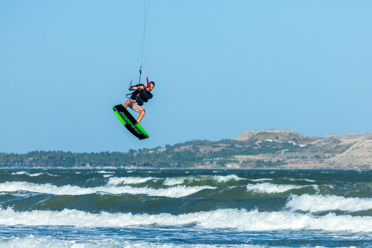 Hombre realizando un impresionante salto de kite surf sobre las olas del océano, mo