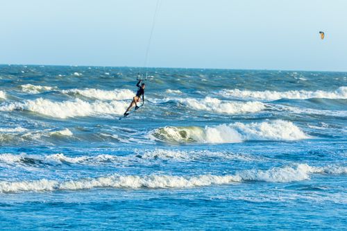 Free Dynamic image of a kitesurfer riding waves on a bright, sunny day, showcasing thrilling ocean adventures. Stock Photo