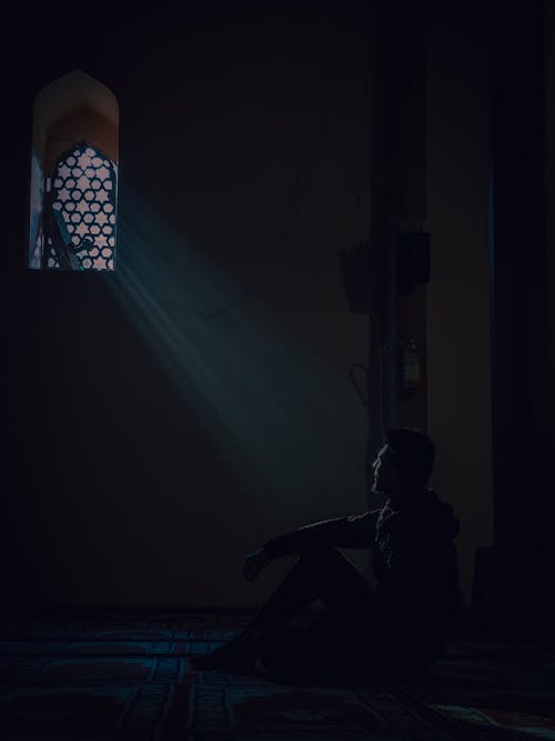 A man sitting in the dark in front of a window