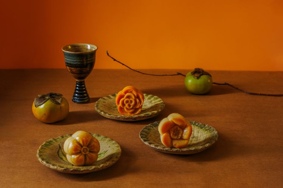 A warm autumn still life featuring persimmons and ceramic plates in a cozy indoor setting.