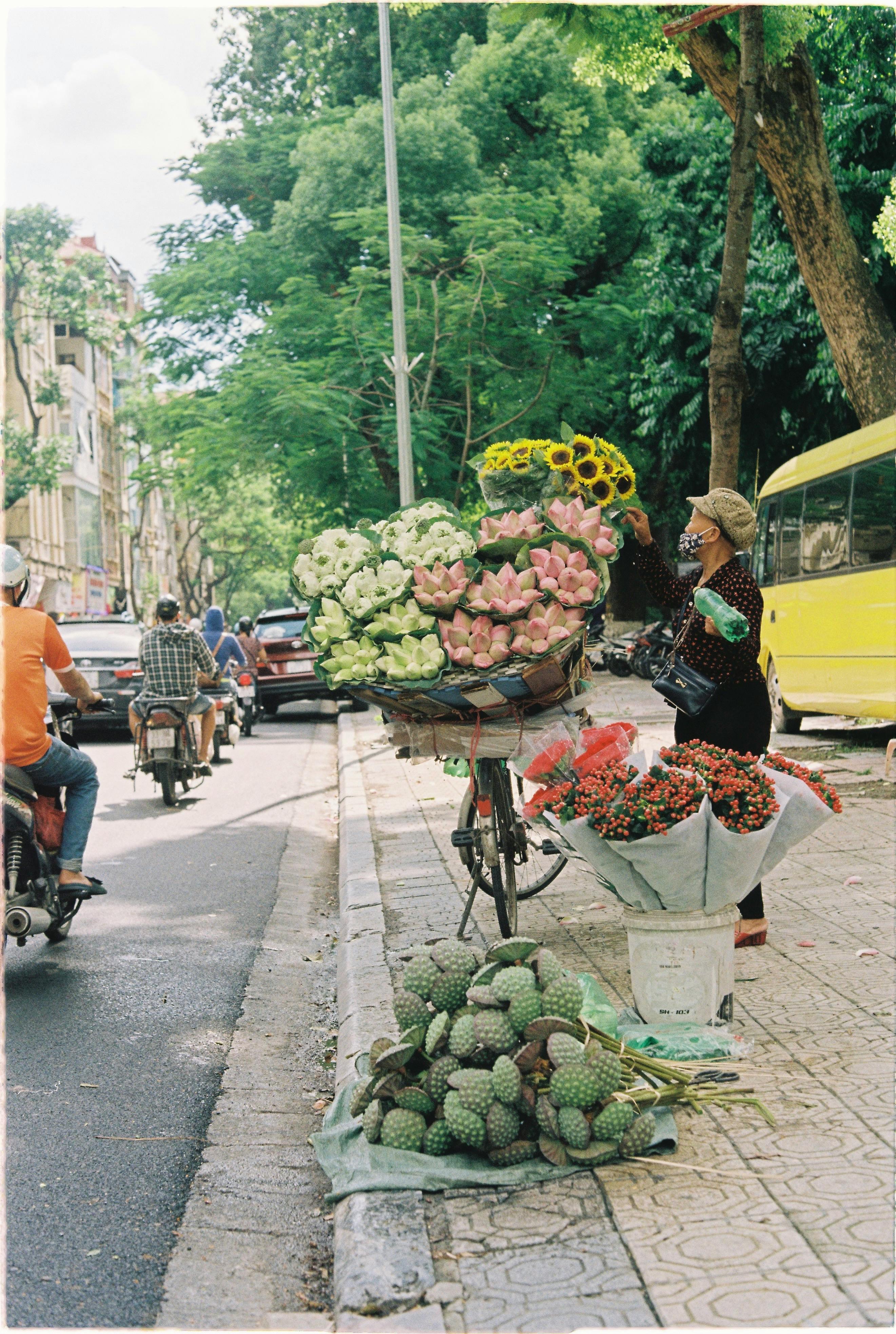 A vibrant flower vendor on a bustling Hanoi street showcasing colorful blooms during the day.