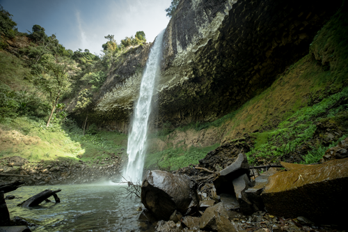 Free A breathtaking waterfall cascading into a serene pool surrounded by forest rocks. Stock Photo