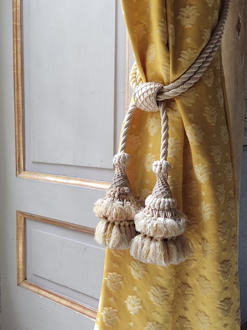 A yellow curtain with tassels hanging from it