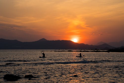 People Canoeing on Sea Coast at Sunset