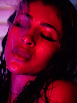 Close-up of a woman with wet hair and pink lighting, evoking a moody and cinematic vibe.