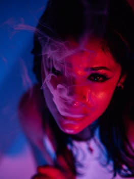 A captivating portrait of a woman enveloped in smoky ambiance with vibrant pink and blue lighting.
