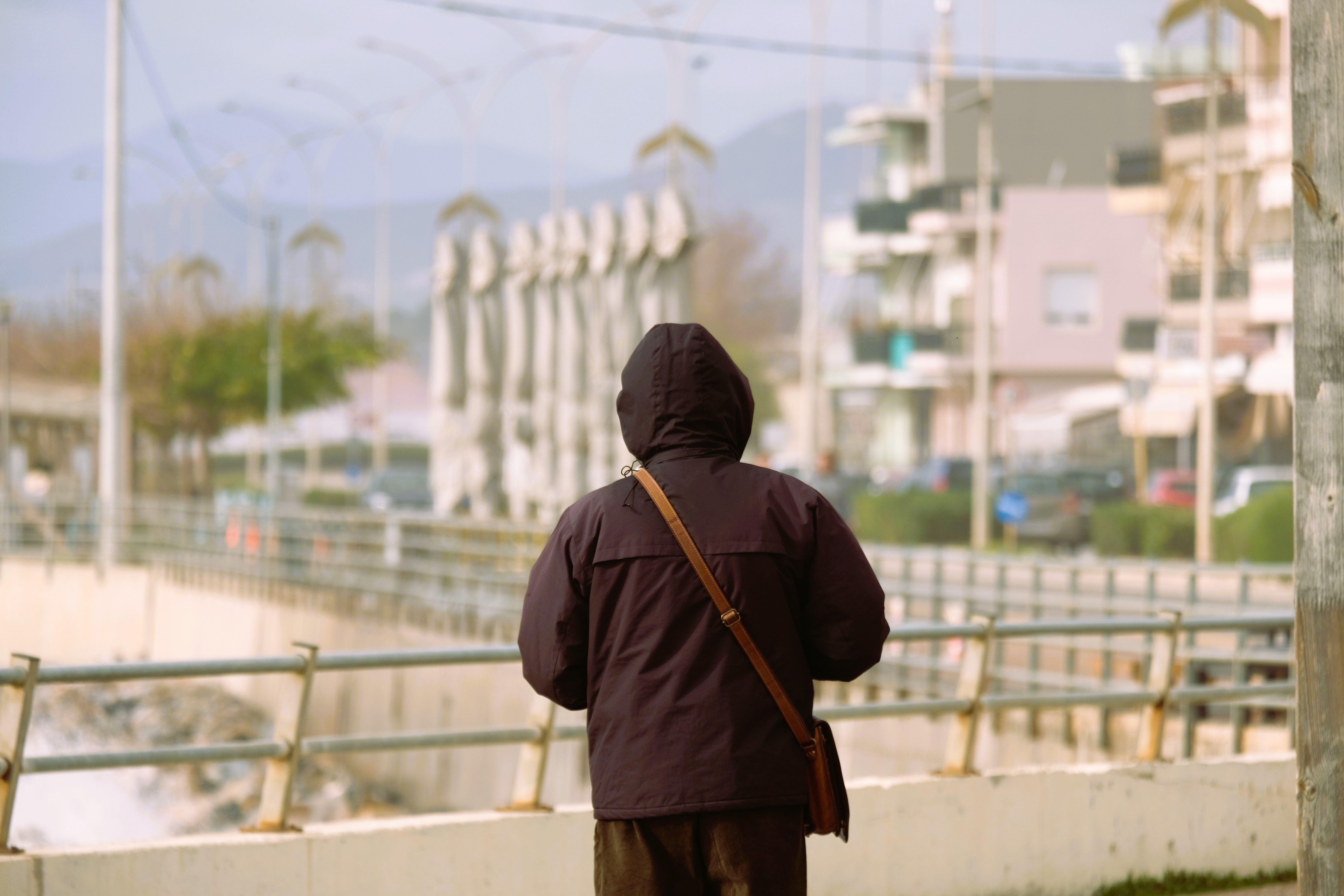 A person wearing a hoodie walks along a seafront promenade in Alexandroupoli, Greece.