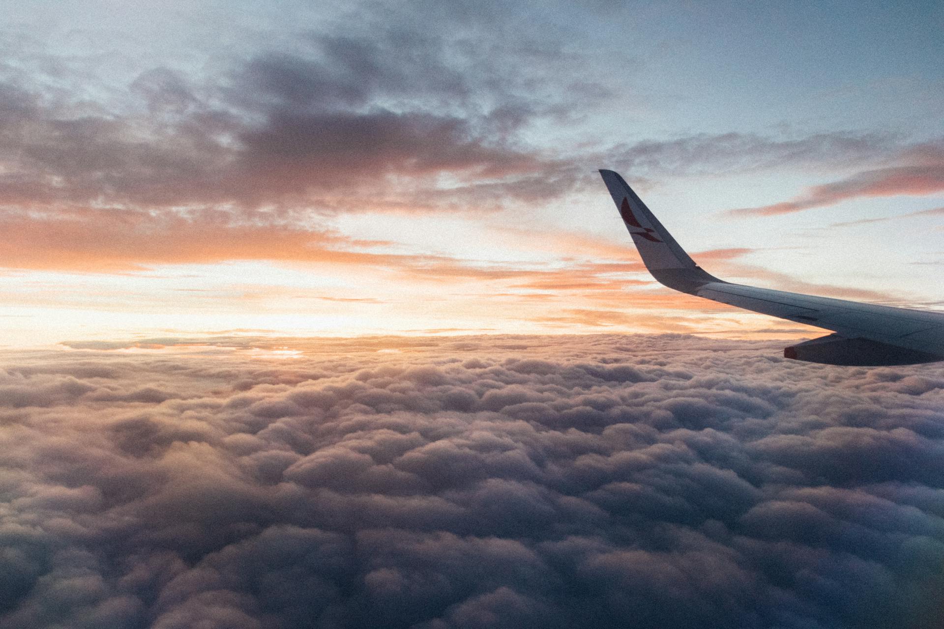 Captivating view from the airplane showcasing clouds and vibrant sunset hues, conveying the essence of air travel.