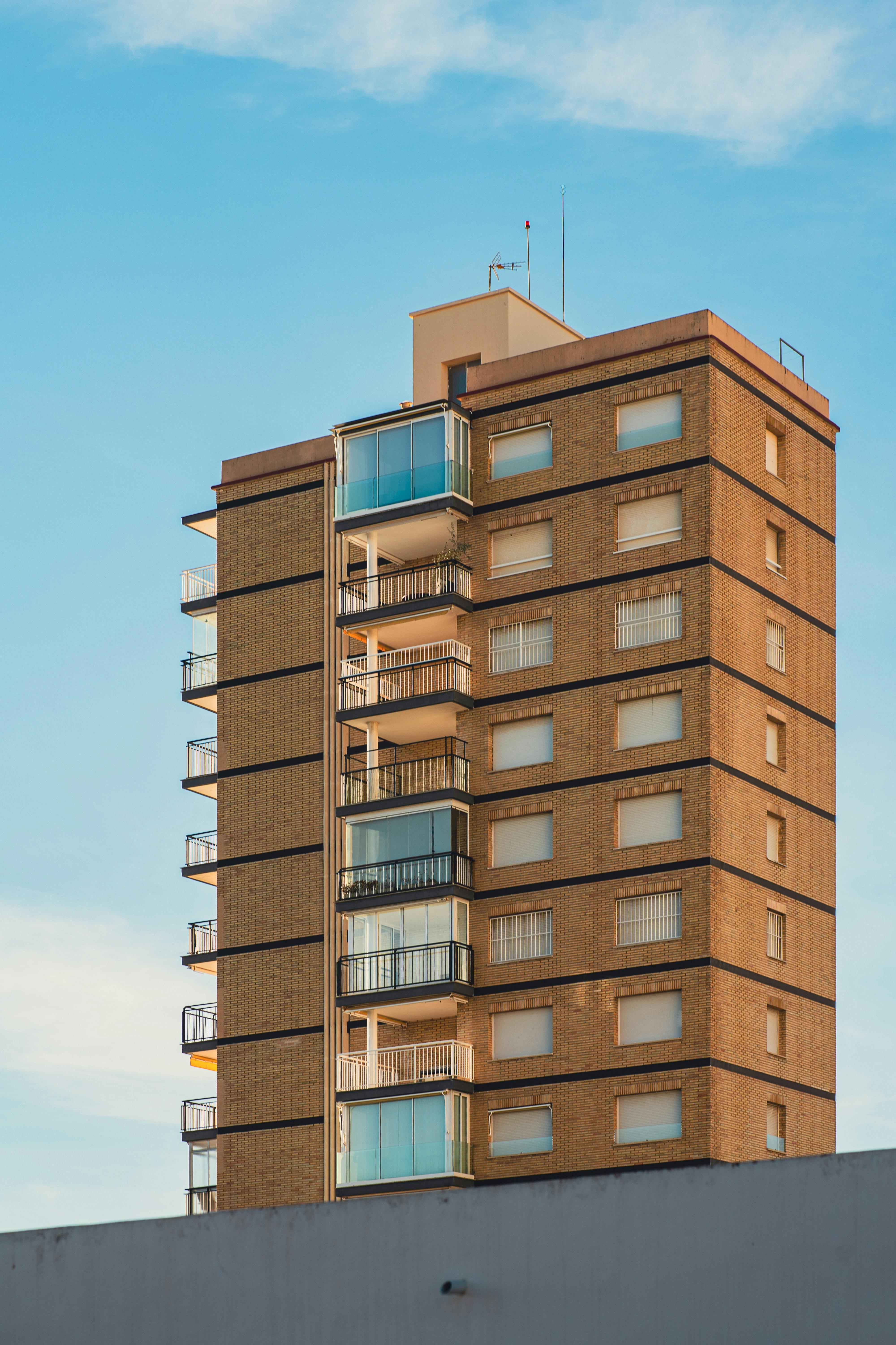 A modern high-rise residential building with balconies under a clear blue sky.