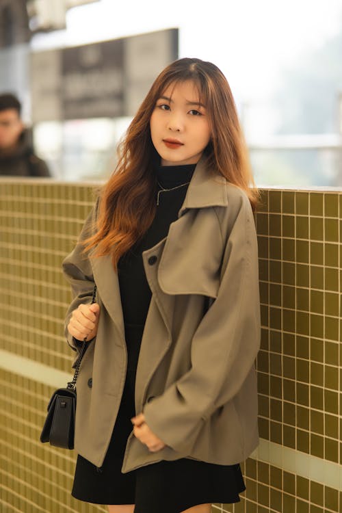 Woman in Coat Standing by Wall