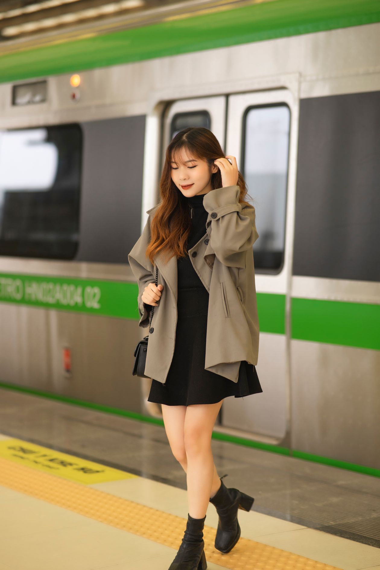 Woman in a neutral coat walking through a city subway station with confident stride