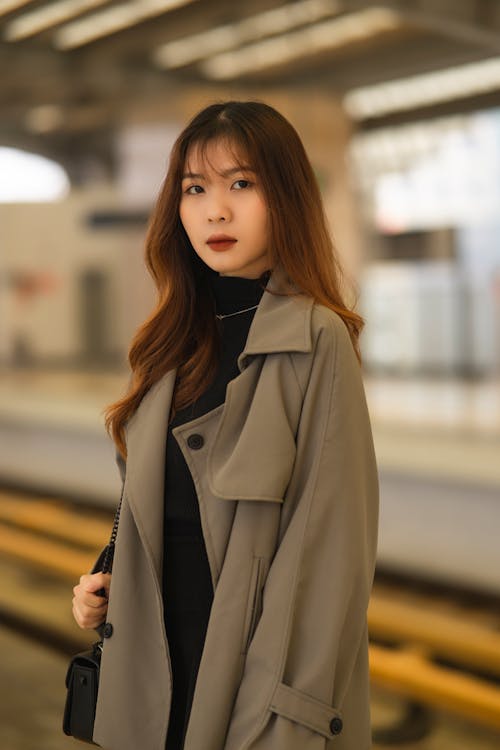 A woman in a trench coat standing at a train station